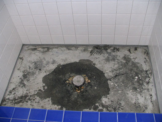 Hot mop shower with open weep holes at drain protected by gravel